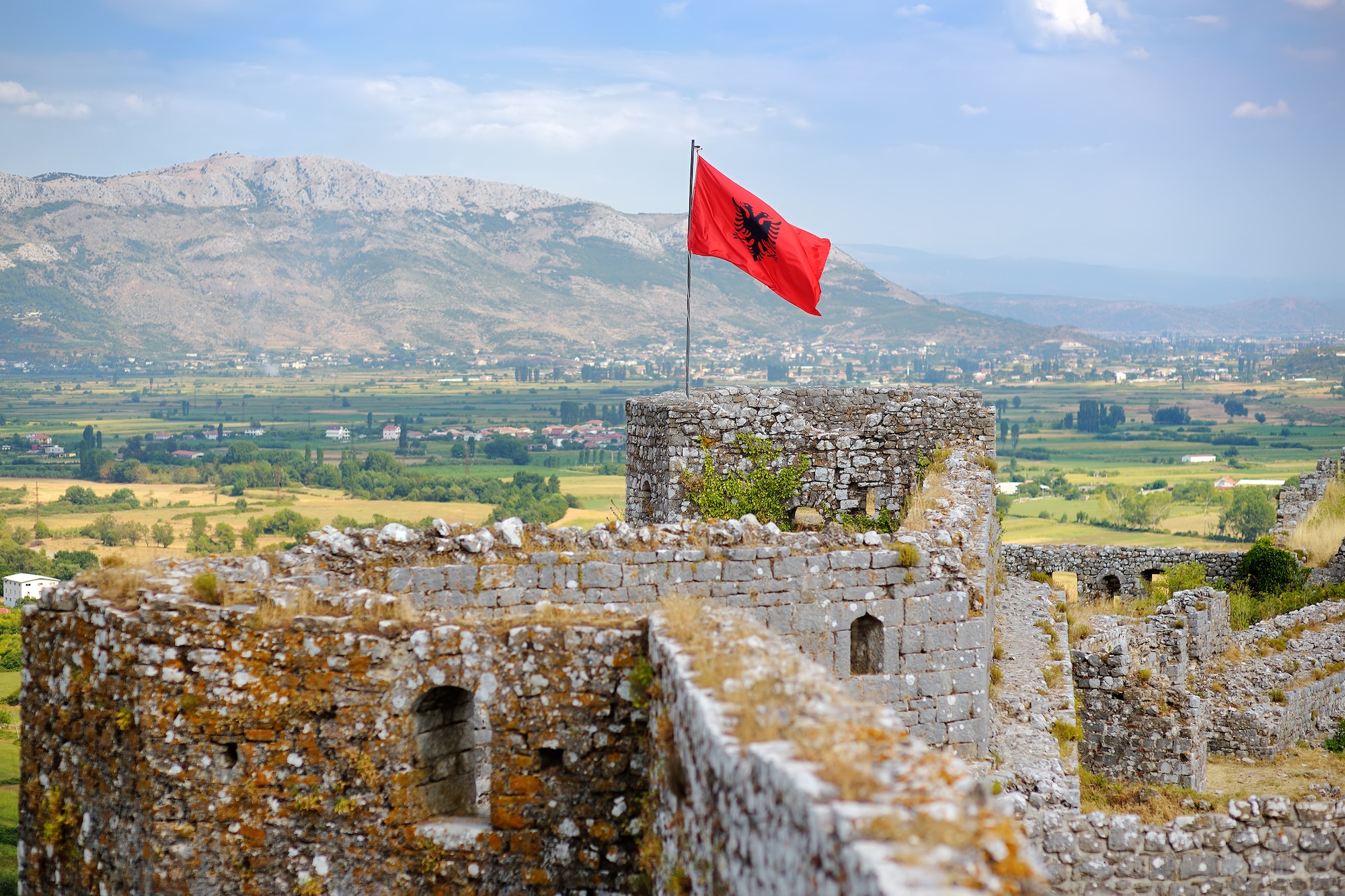 Red Albanian flag with black eagle waving over wall of Fortress Rozafa near Shkodra city